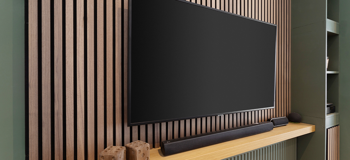 A modern home office in Dublin featuring a full-height oak acoustic slatted wall panel, designed to reduce echo and improve productivity for remote work.